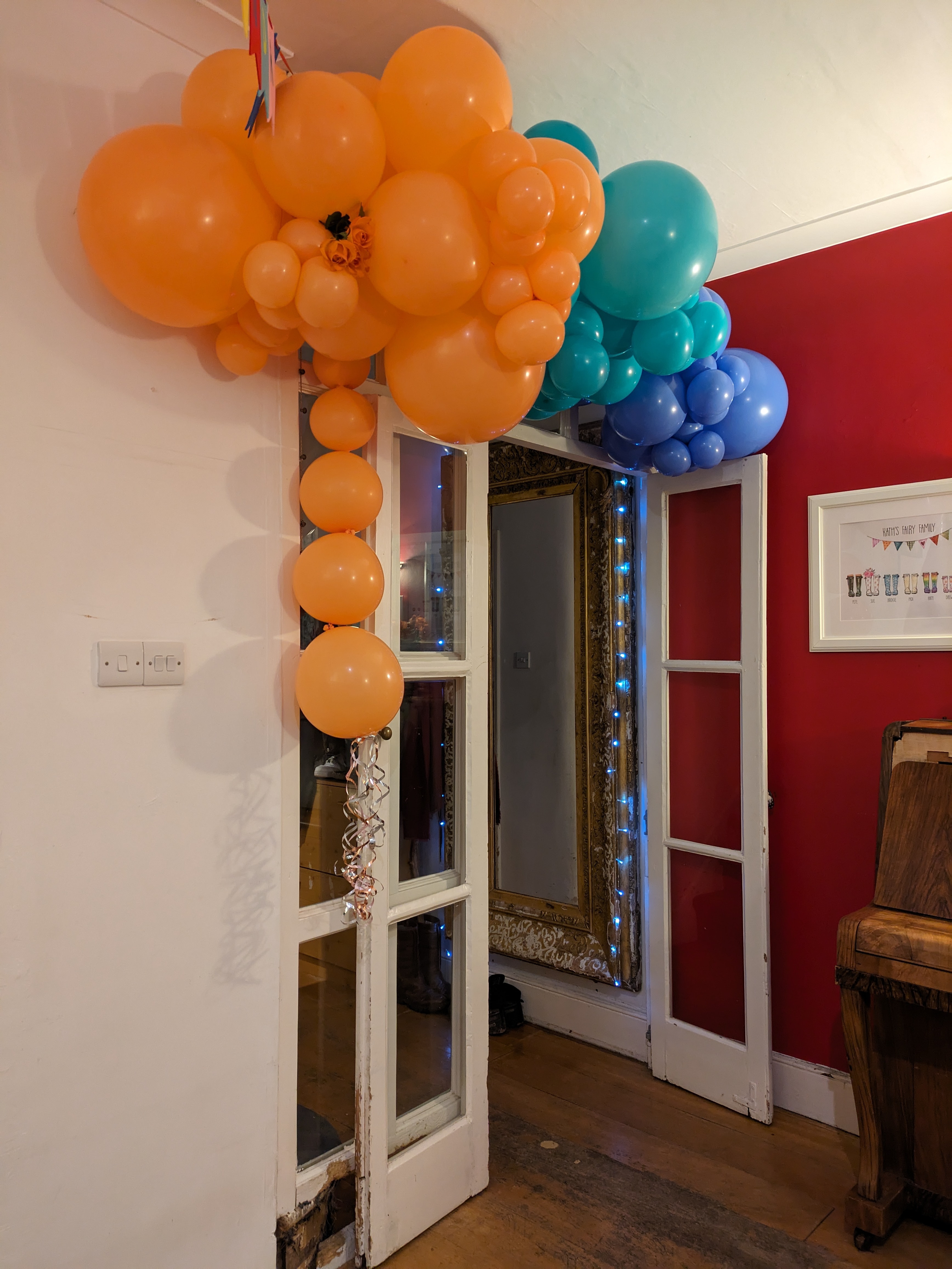 Orange, green and blue balloons hang around a doorway