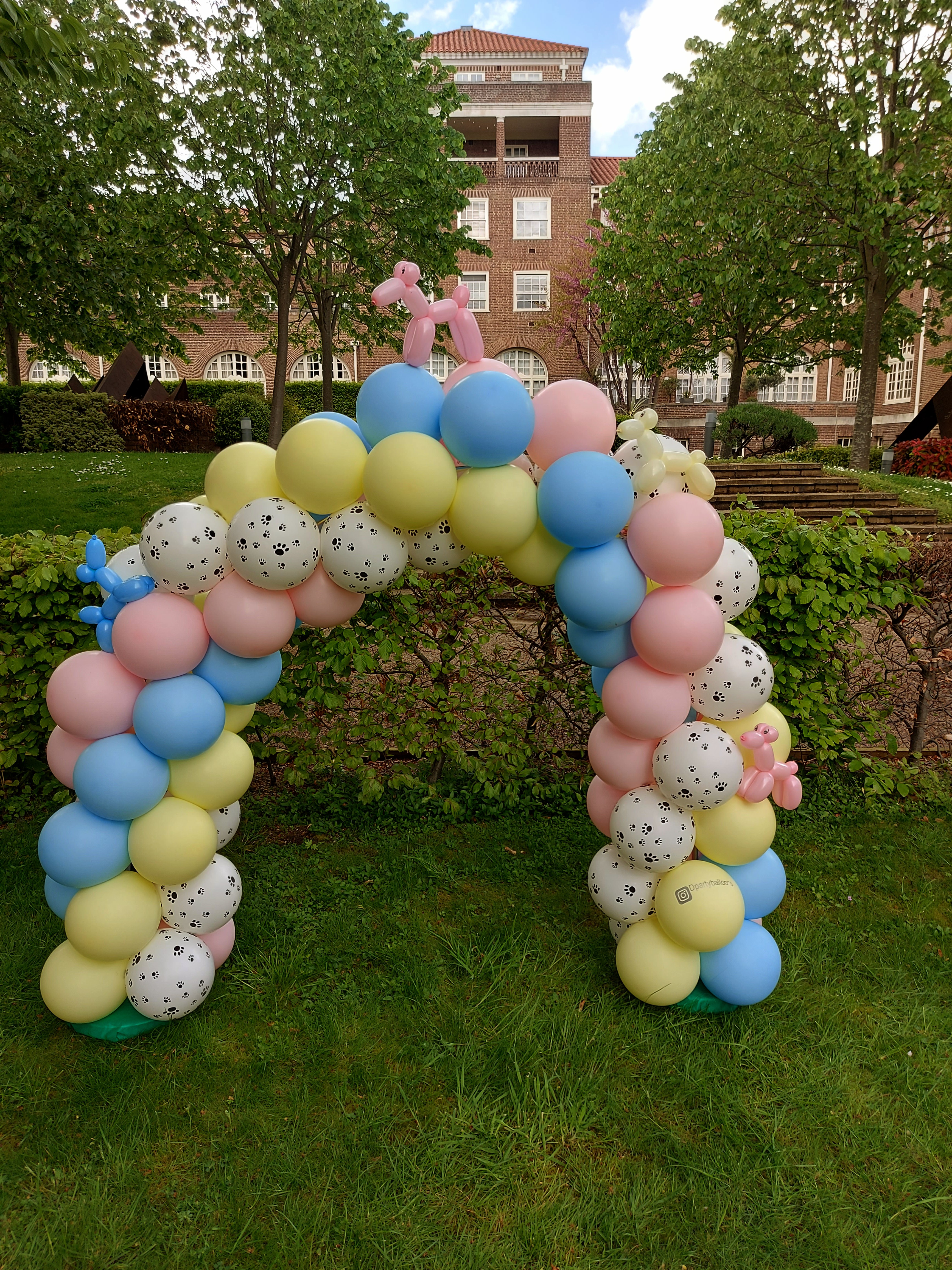 A twisting 4-colour arch in pastel shades, dotted with paw prints and adorned with balloon sausage dogs