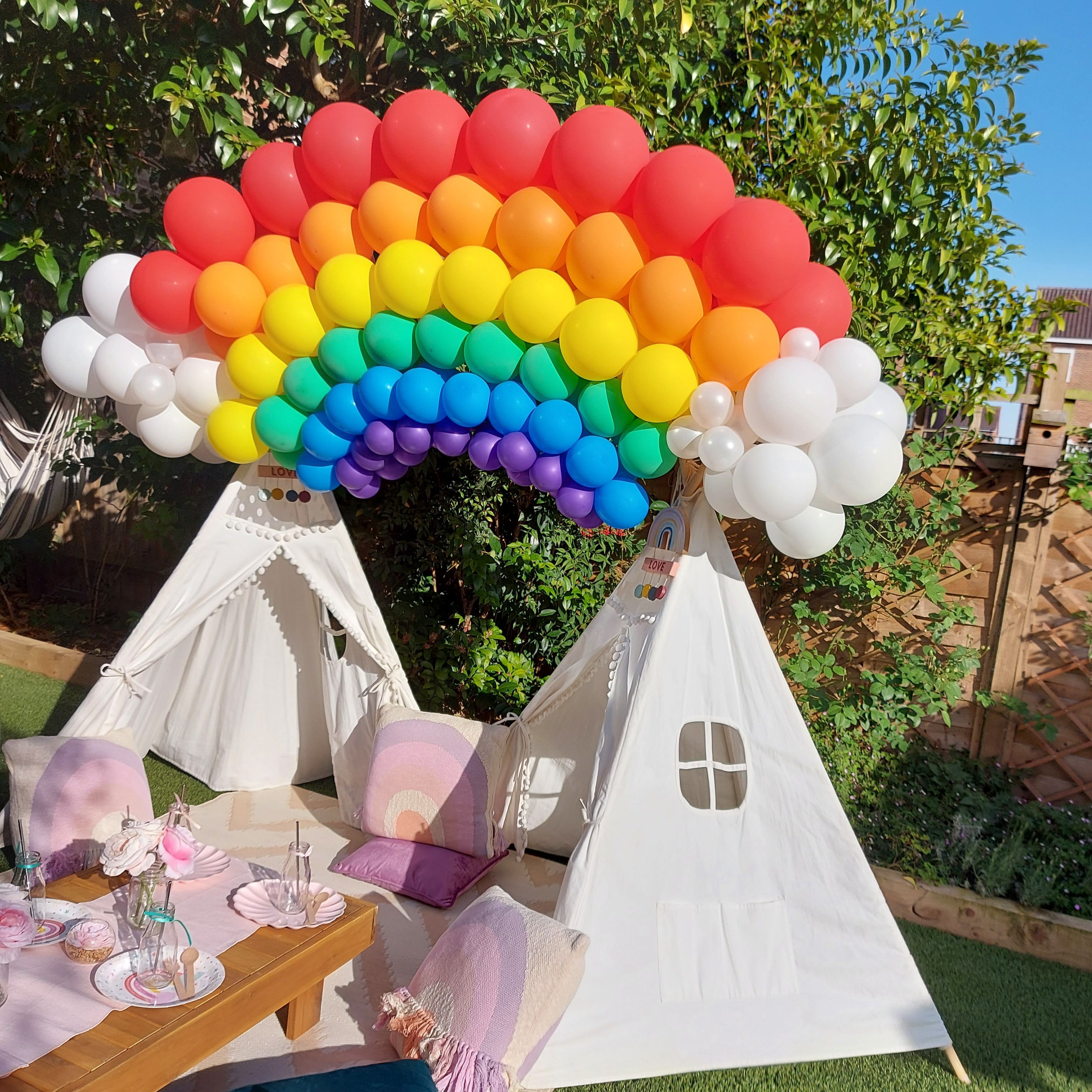 A six-colour rainbow arch, jumping from one white cloud to another