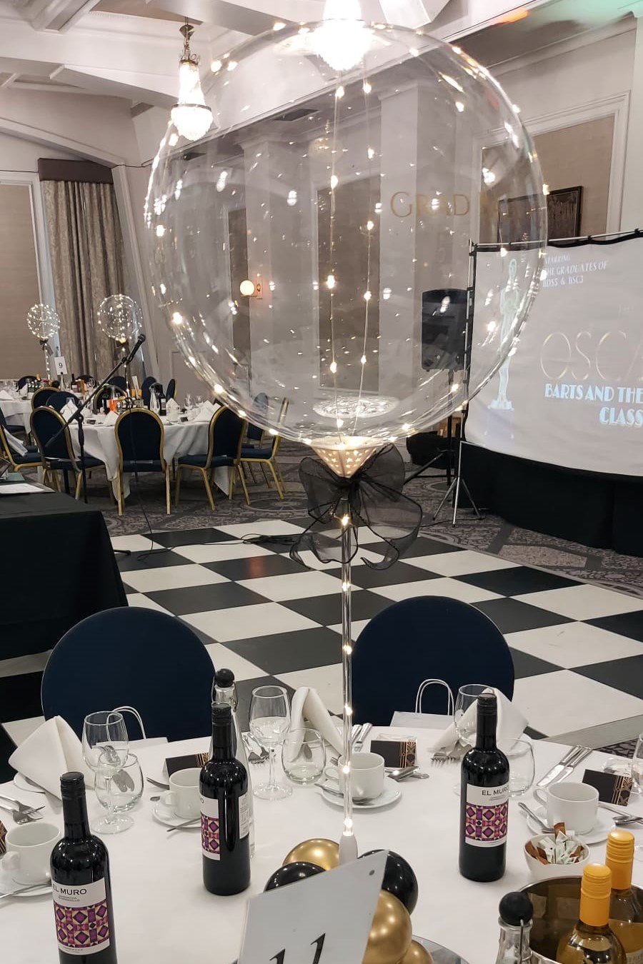A transpoarent balloon lined with white LEDs stands above a table